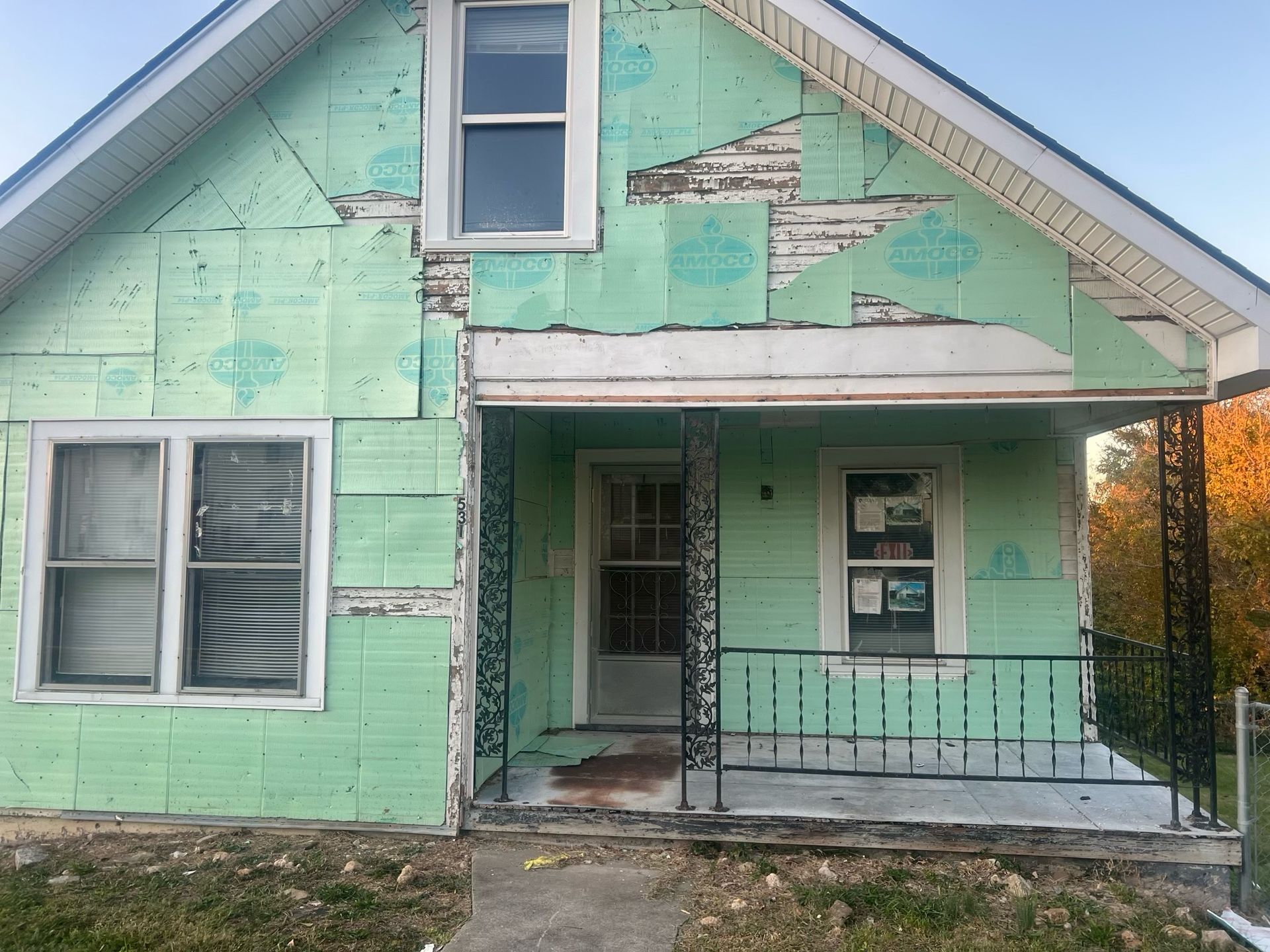 Weathered mint-green house with peeling paint and a small front porch