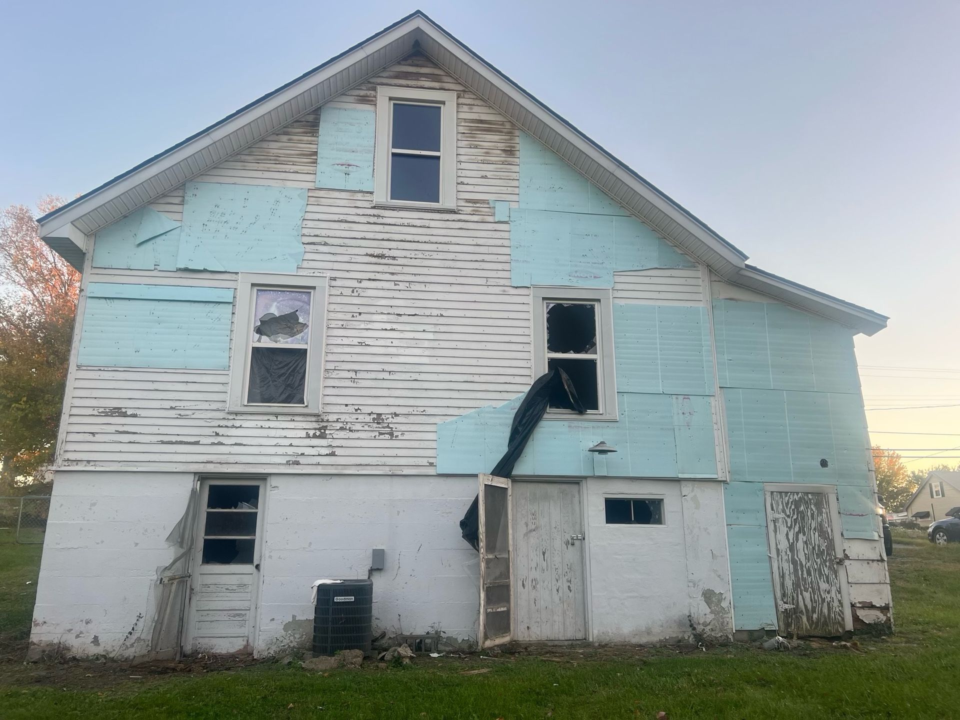 Old weathered two-story house with peeling white and blue paint and broken siding