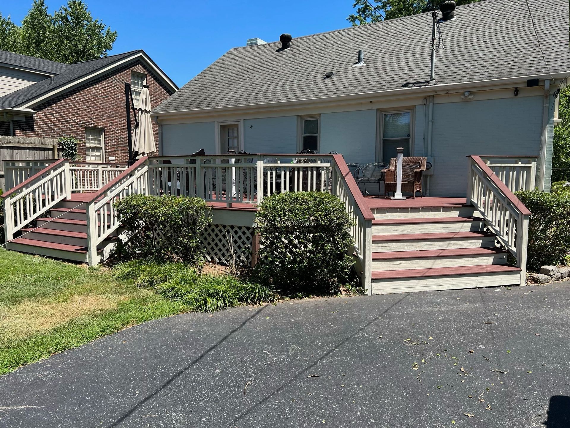 Front steps and decks on a suburban house with white railings and pink trim, beside a driveway