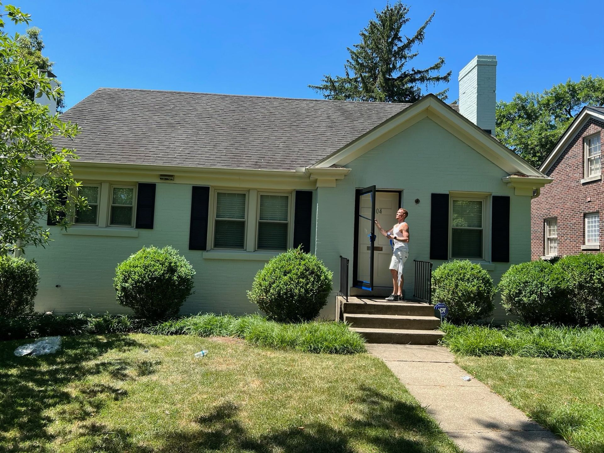 Single-story house with a person standing on the front steps under a bright blue sky