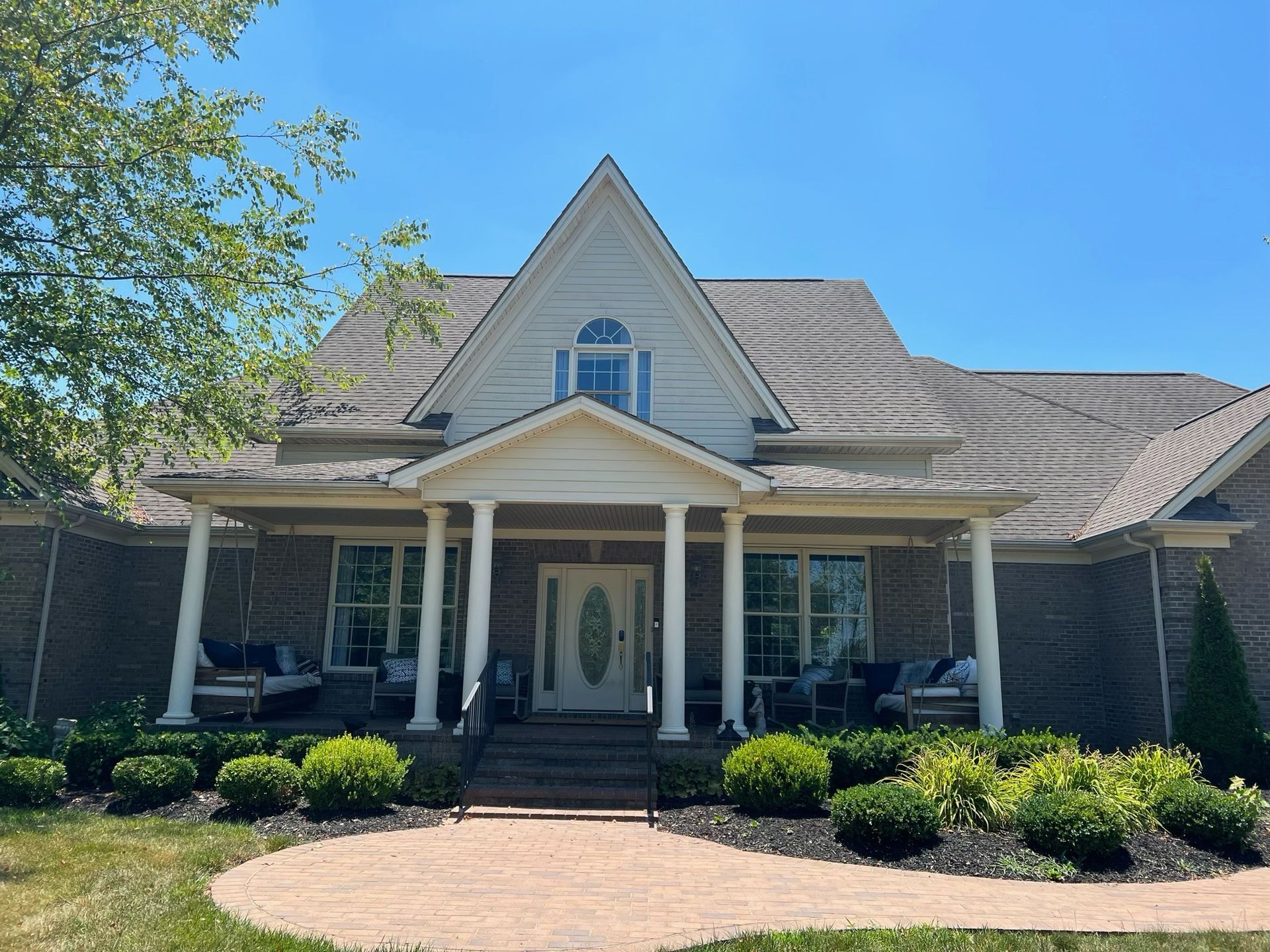 Front view of a suburban house with a peaked roof, brick exterior, and landscaped front yard.