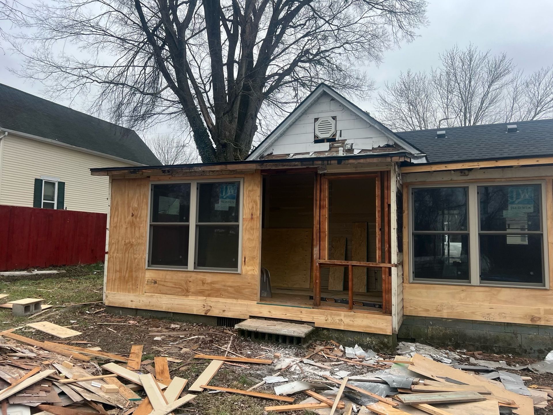 Partially built wooden house with plywood siding and debris scattered in front yard