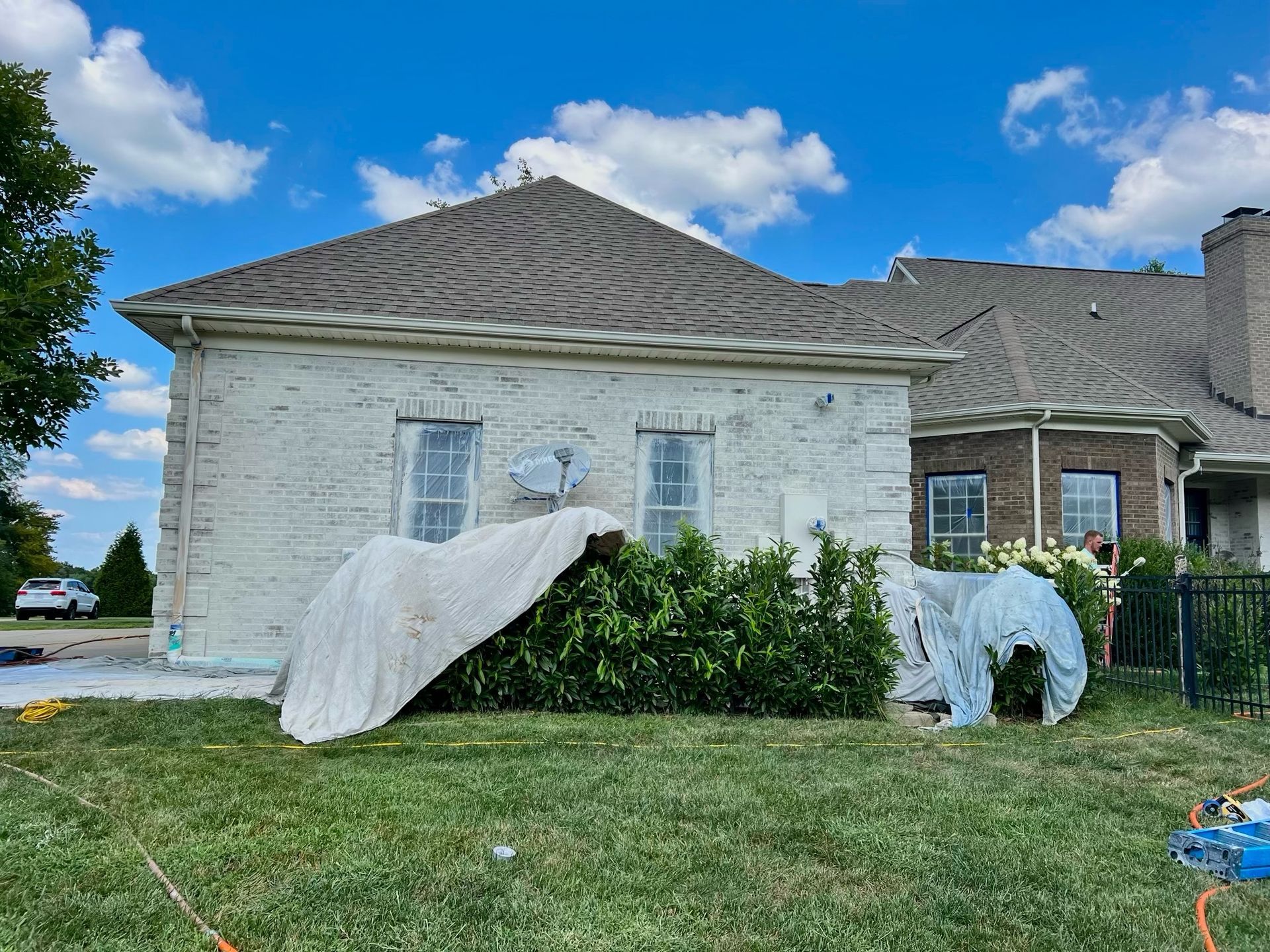 White house with white ghost decorations on the lawn under a bright blue sky.