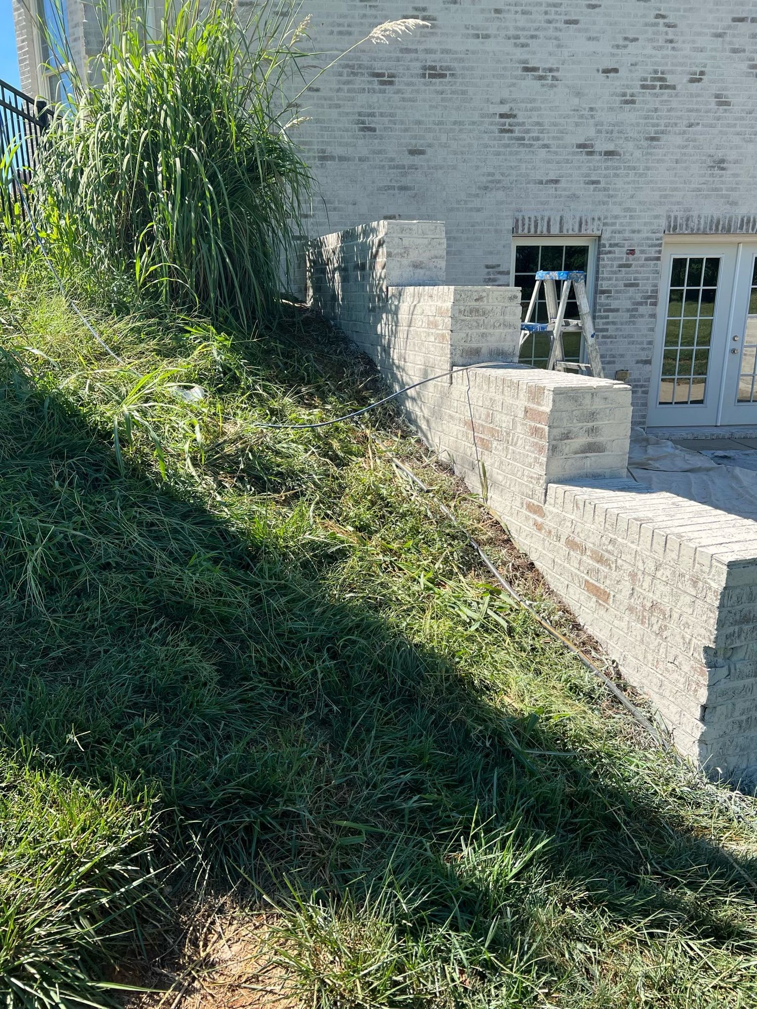 Stone house with a sloped, ivy-covered hillside and small windows beside a paved area