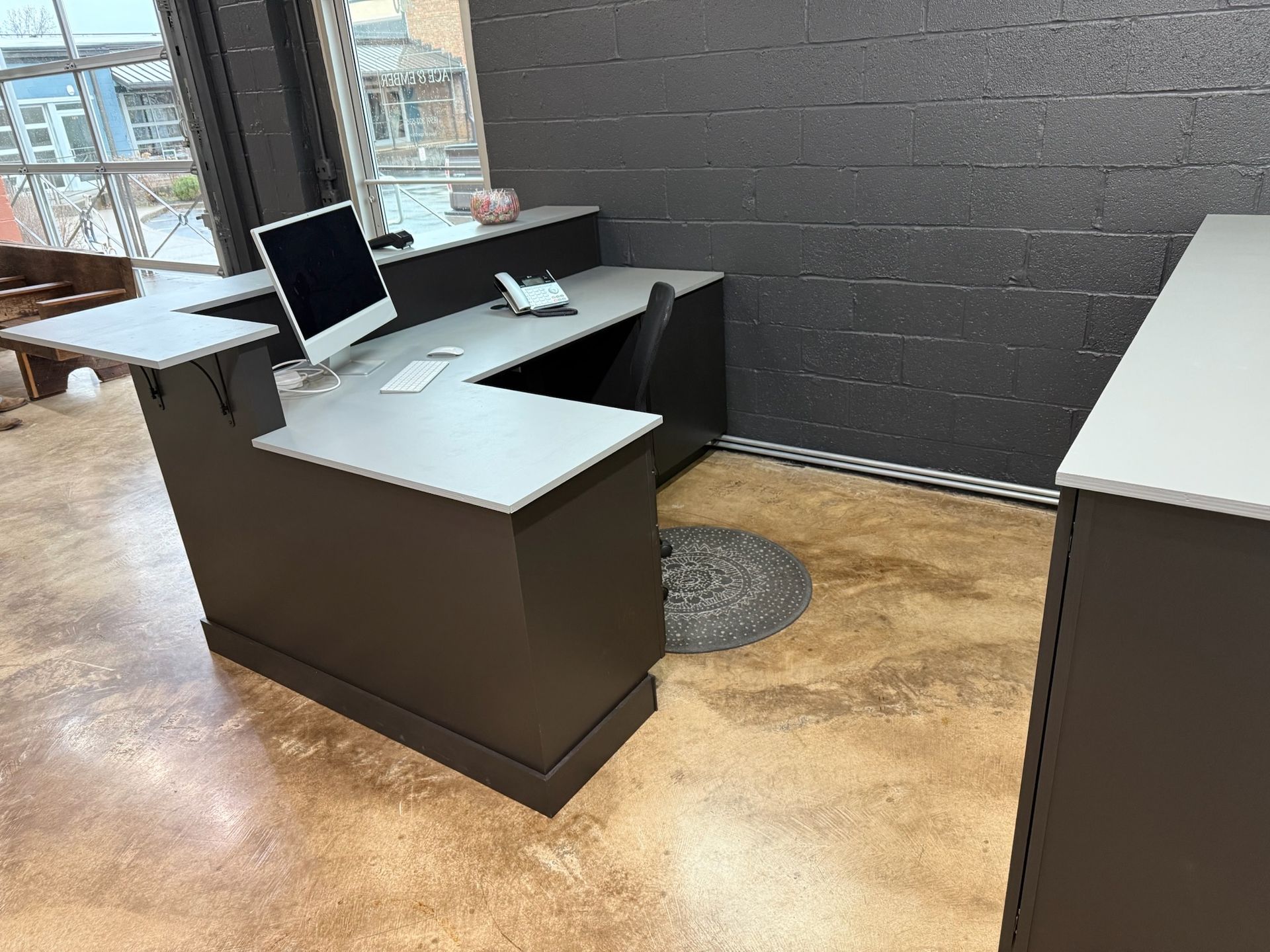 Office desk with computer monitor and papers in a modern lobby beside large windows