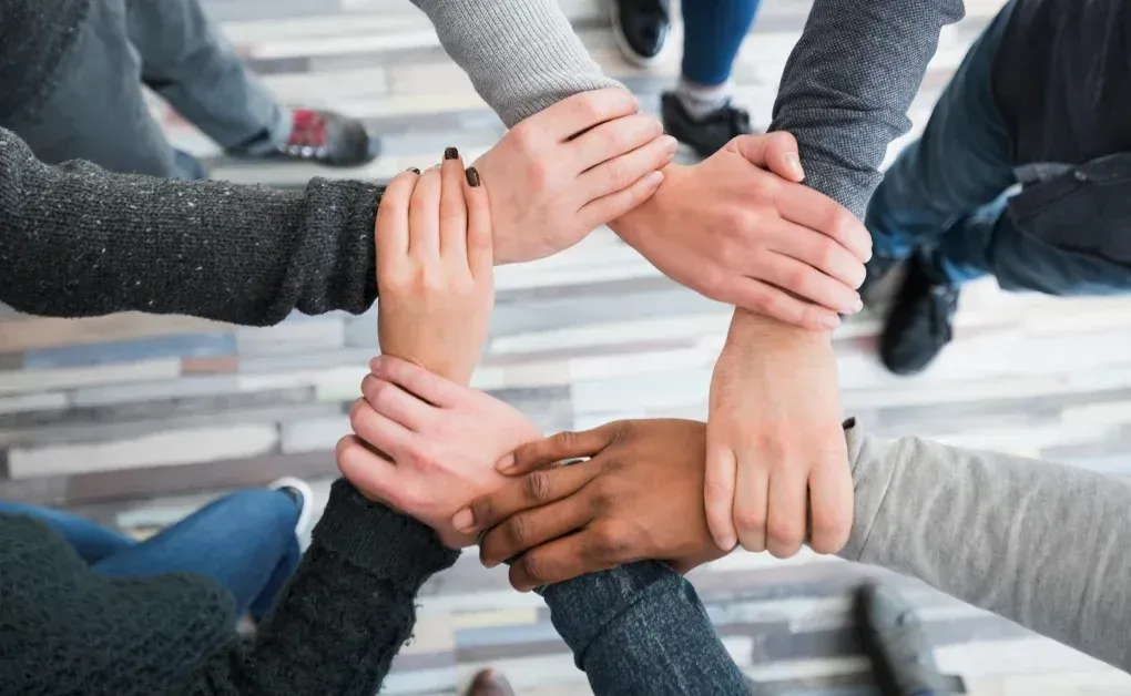 grupo de personas junta sus manos formando un círculo | Plurum | Transformación cultural y creación de entornos de bienestar
