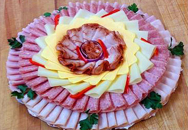 A tray of meat and cheese on a wooden table.
