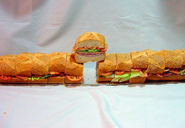 A very long sandwich with a slice taken out of it