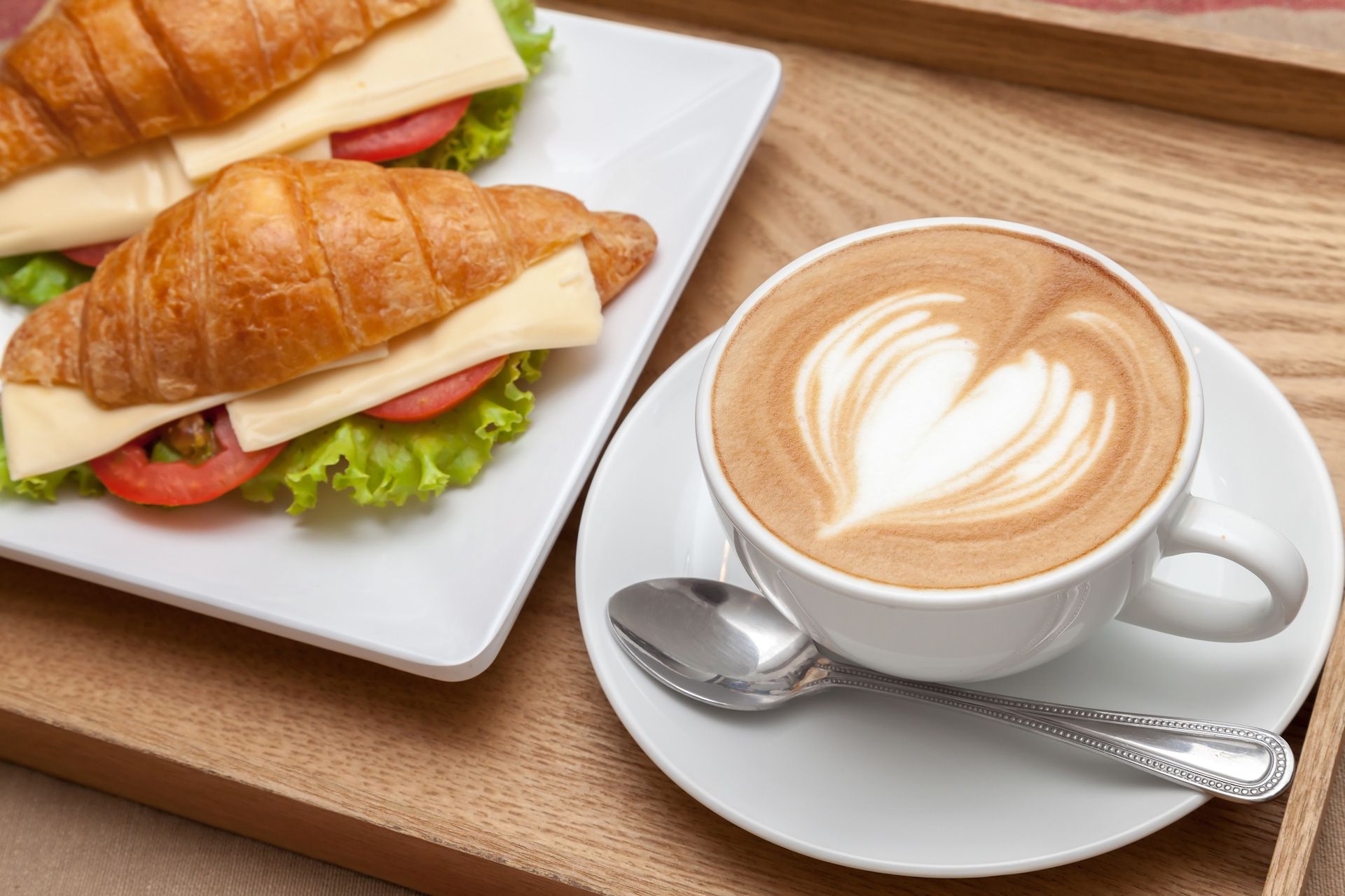 Two croissants and a cup of coffee on a wooden tray.