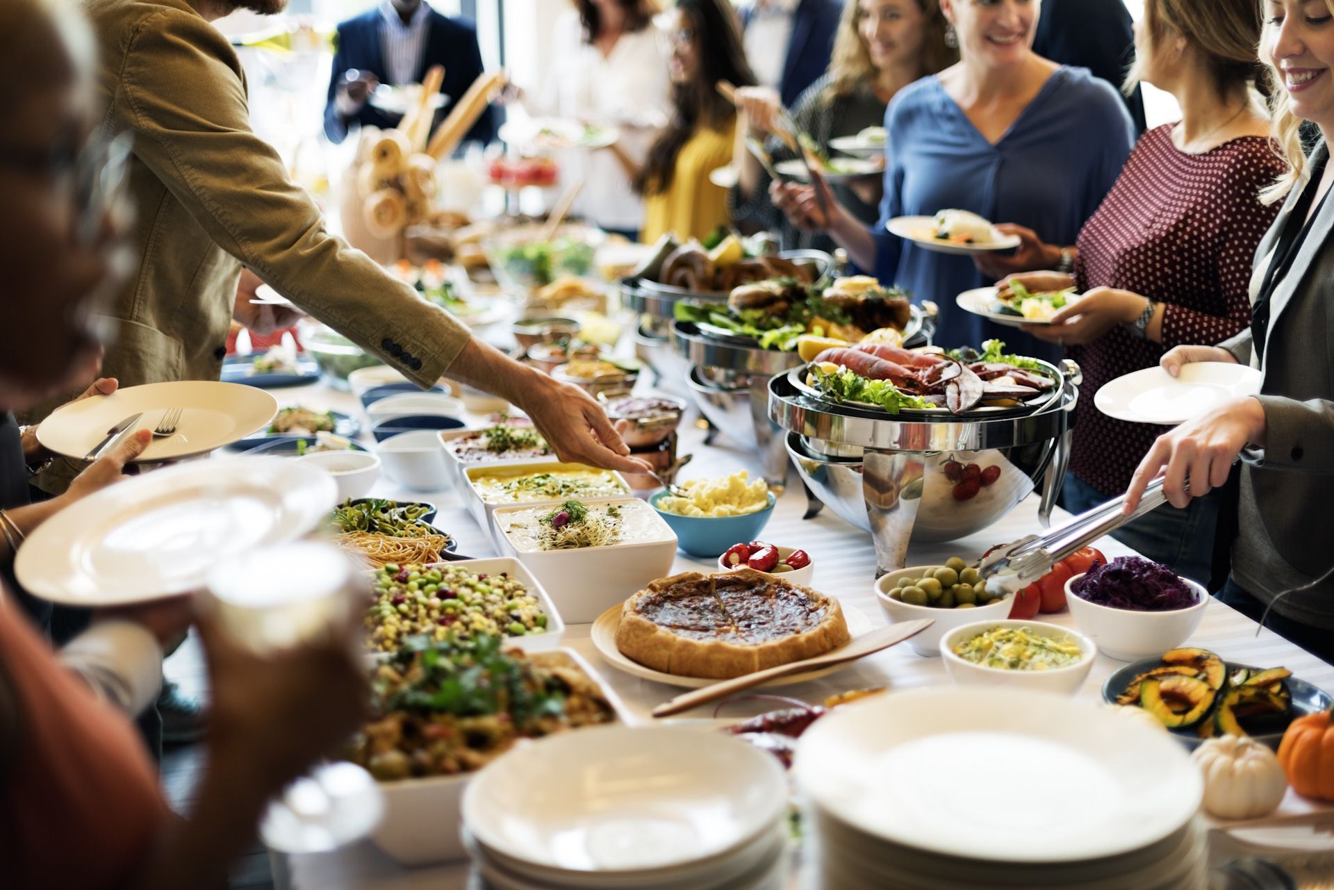 A group of people are standing around a long table filled with food.
