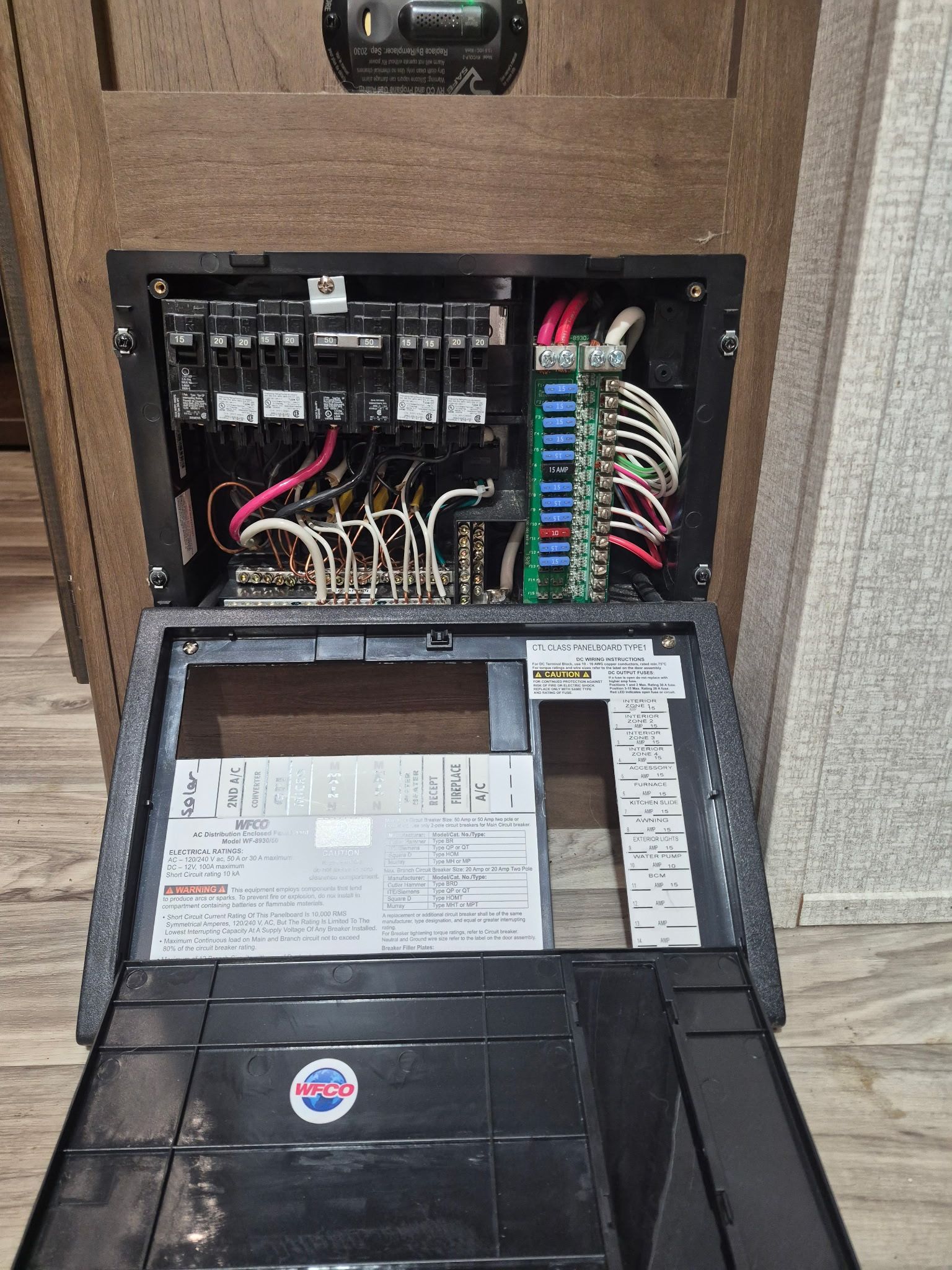 Technician connecting hoses to RV water system outside the open service panel