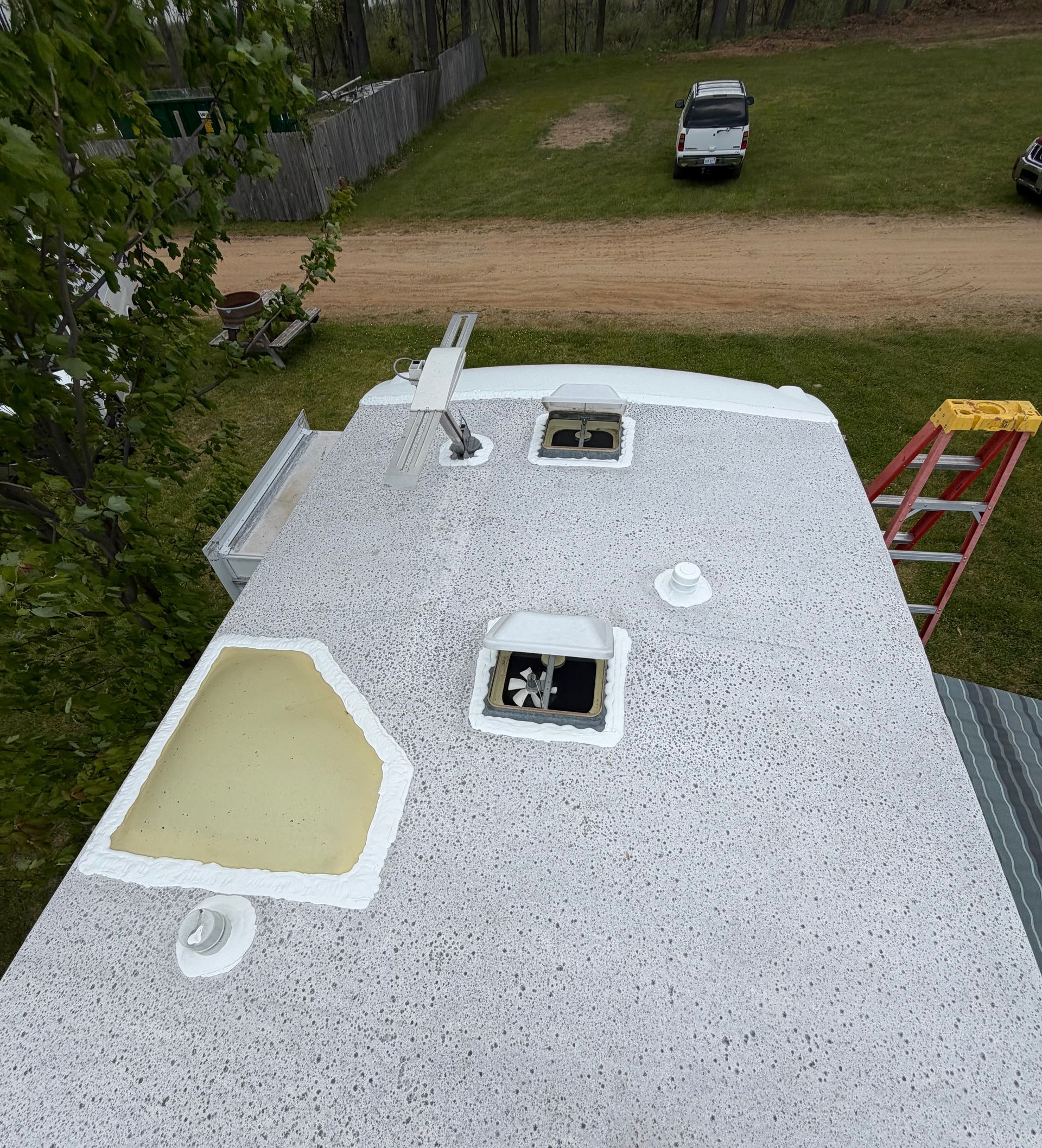 Person caulking the seam of a white RV roof with a caulking gun