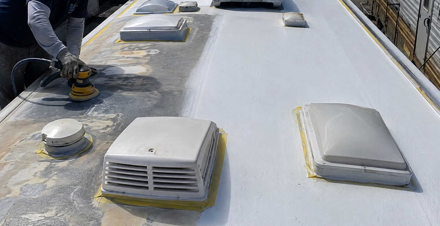Rooftop with white skylight vents and a worker kneeling near a repair area