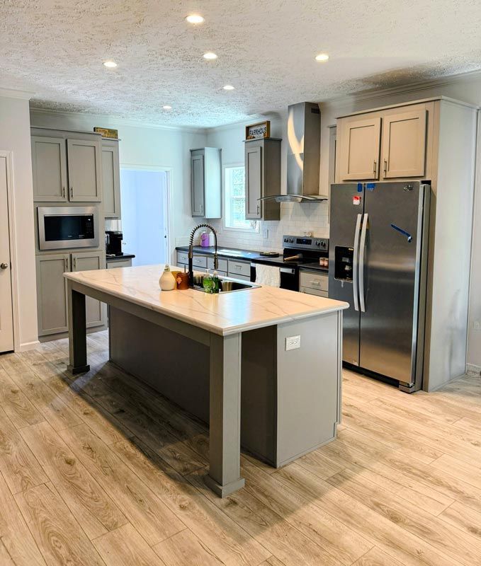 Modern gray kitchen with island, stainless appliances, and light wood flooring