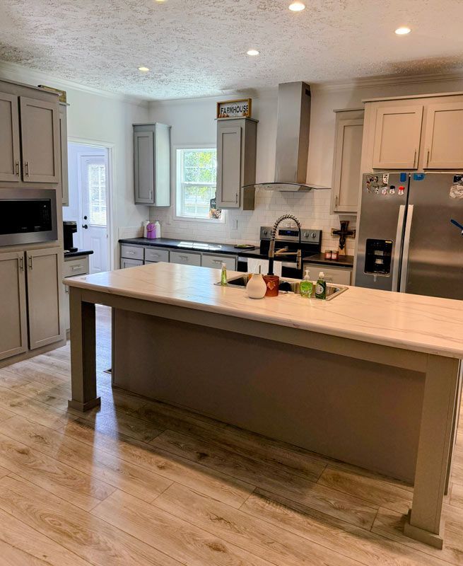 Bright modern kitchen with large island, white cabinets, stainless appliances, and light wood flooring