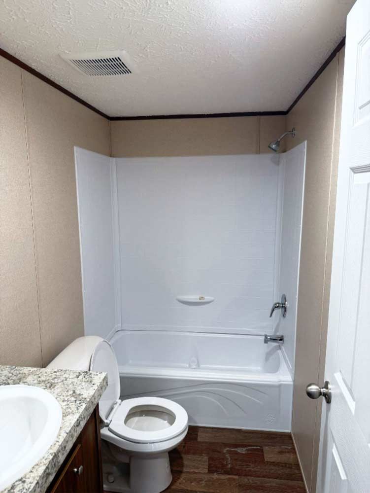 Small bathroom with a toilet, sink, and white shower curtain over the tub.