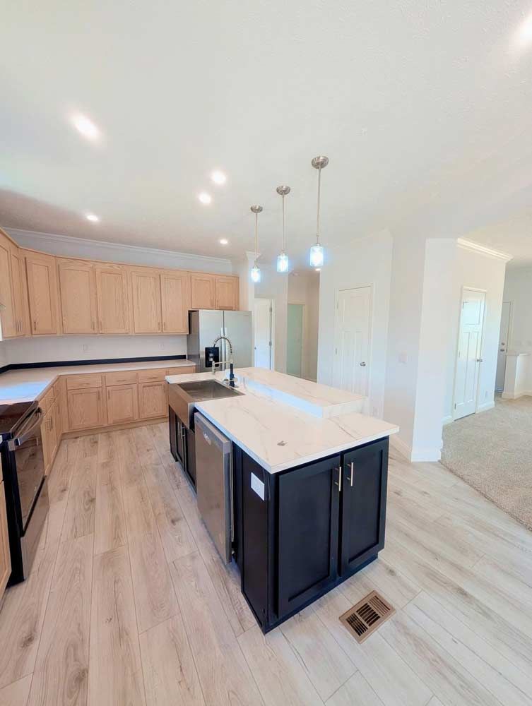 Bright modern kitchen with light wood cabinets, white island, pendant lights, and hardwood floors