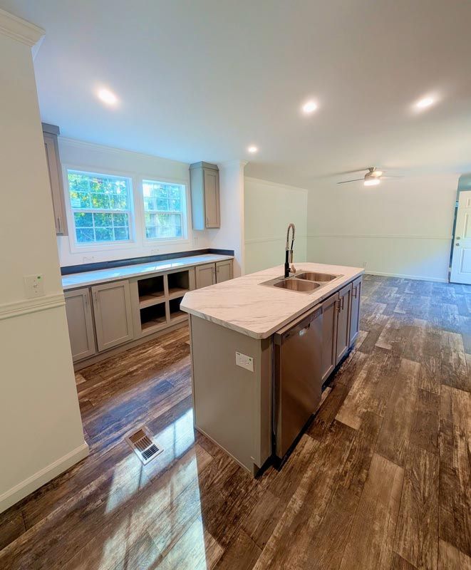 Bright modern kitchen with island, white cabinets, wood floors, and large windows