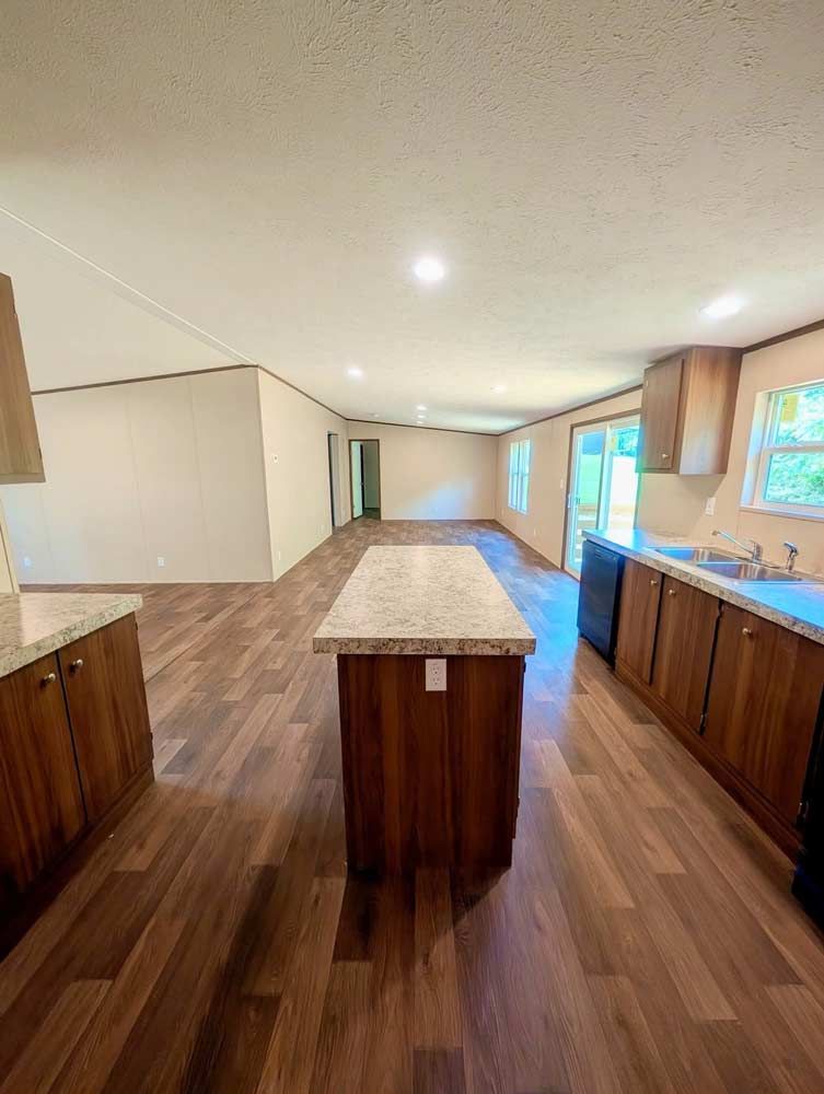 Bright open kitchen with wood floors, central island, white walls, and windows along the right side.