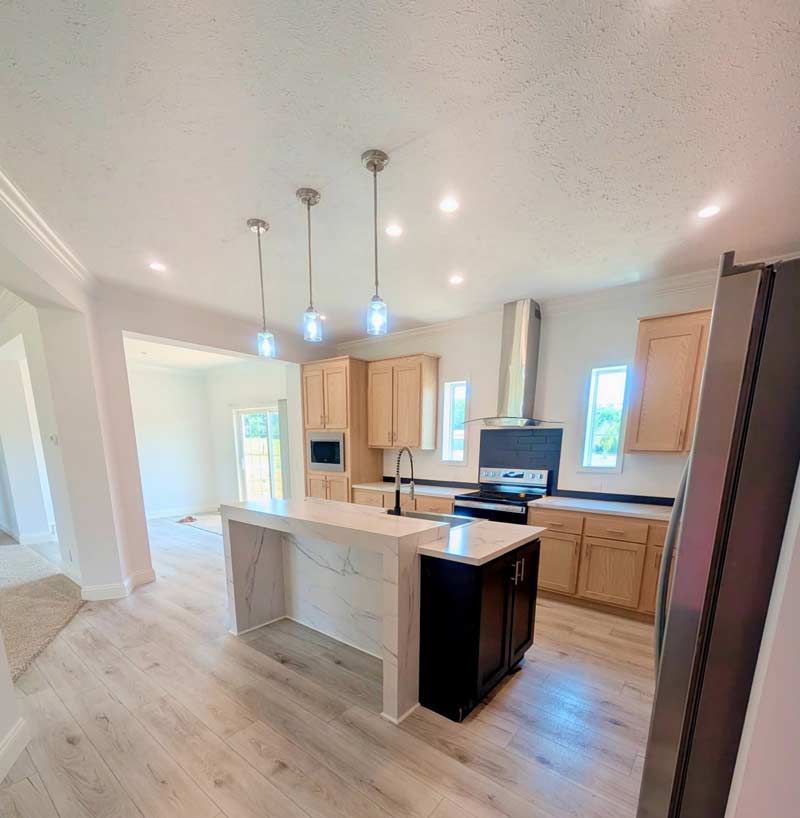 Bright, modern kitchen with a large island, light wood cabinets, stainless appliances, and pendant lights