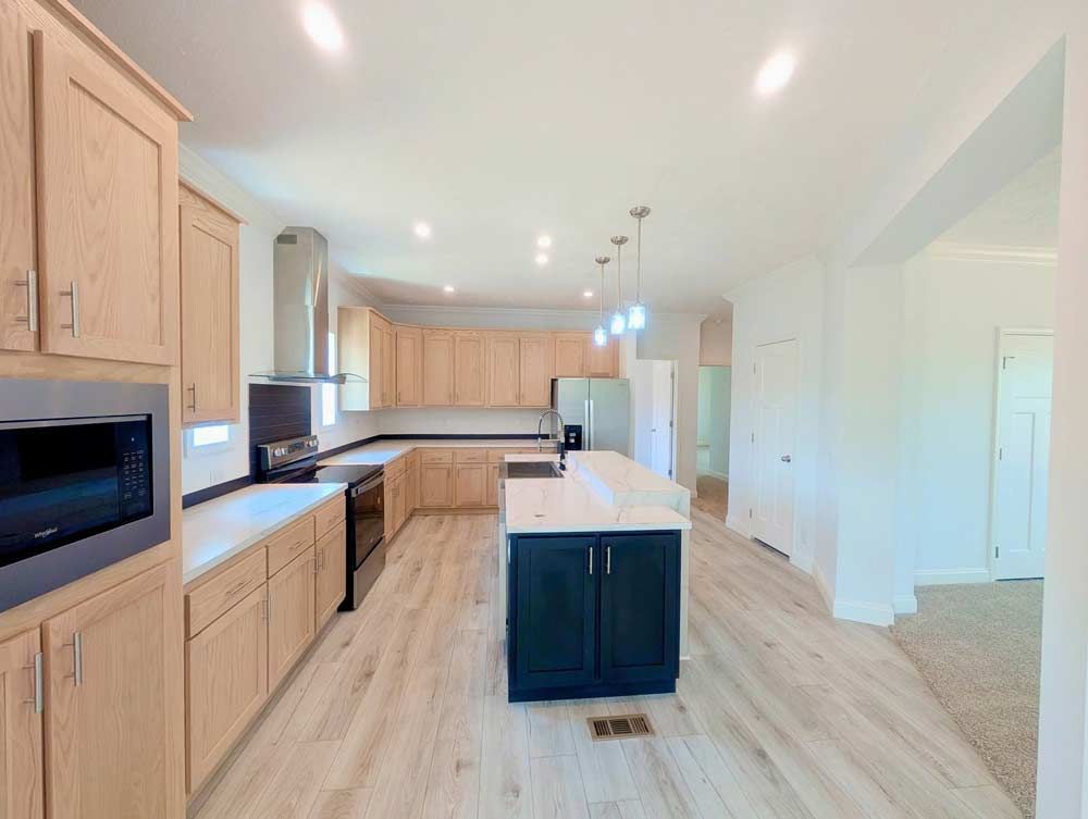 Bright modern kitchen with light wood cabinets, white island, and hardwood floors