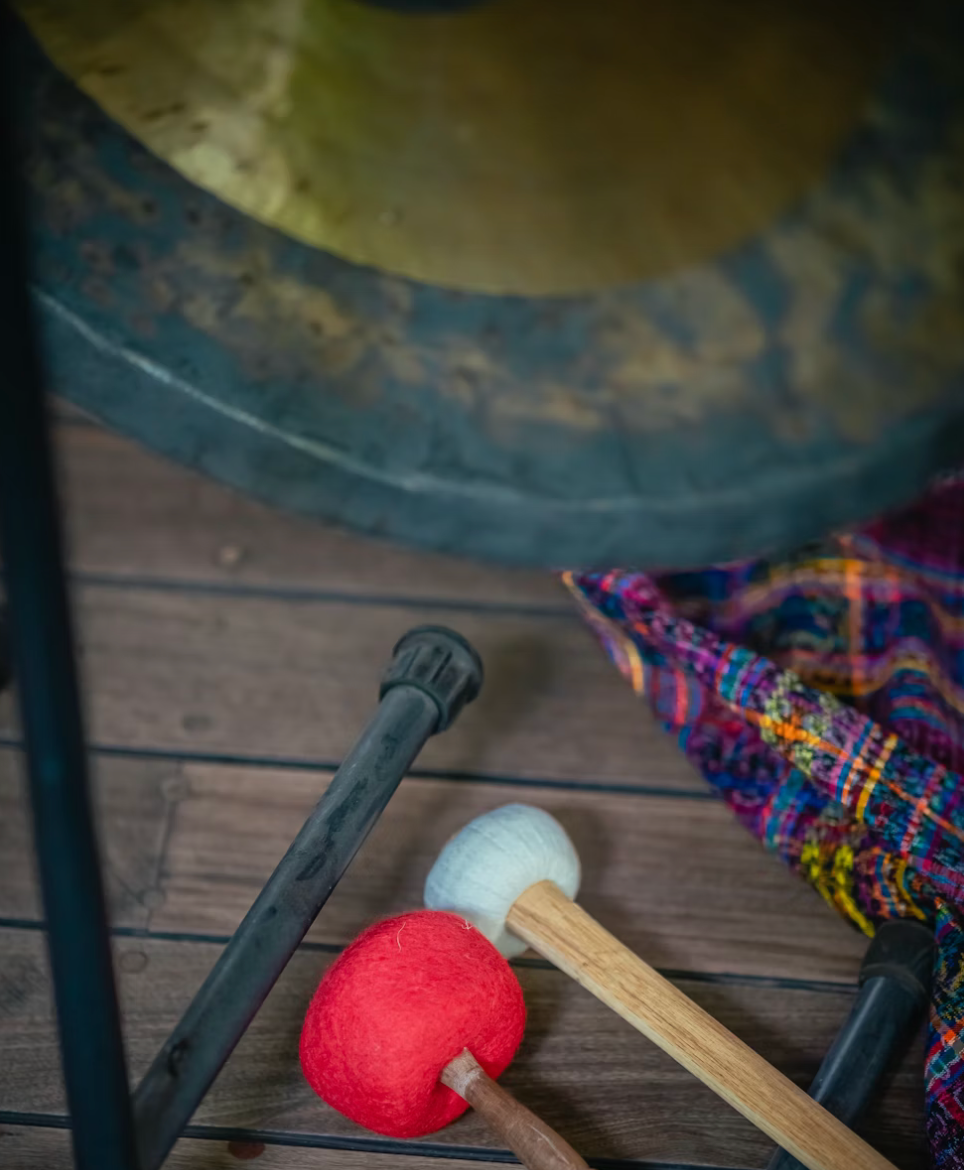 Two mallets beside a drum, with a red and a white felt head on a wooden floor.