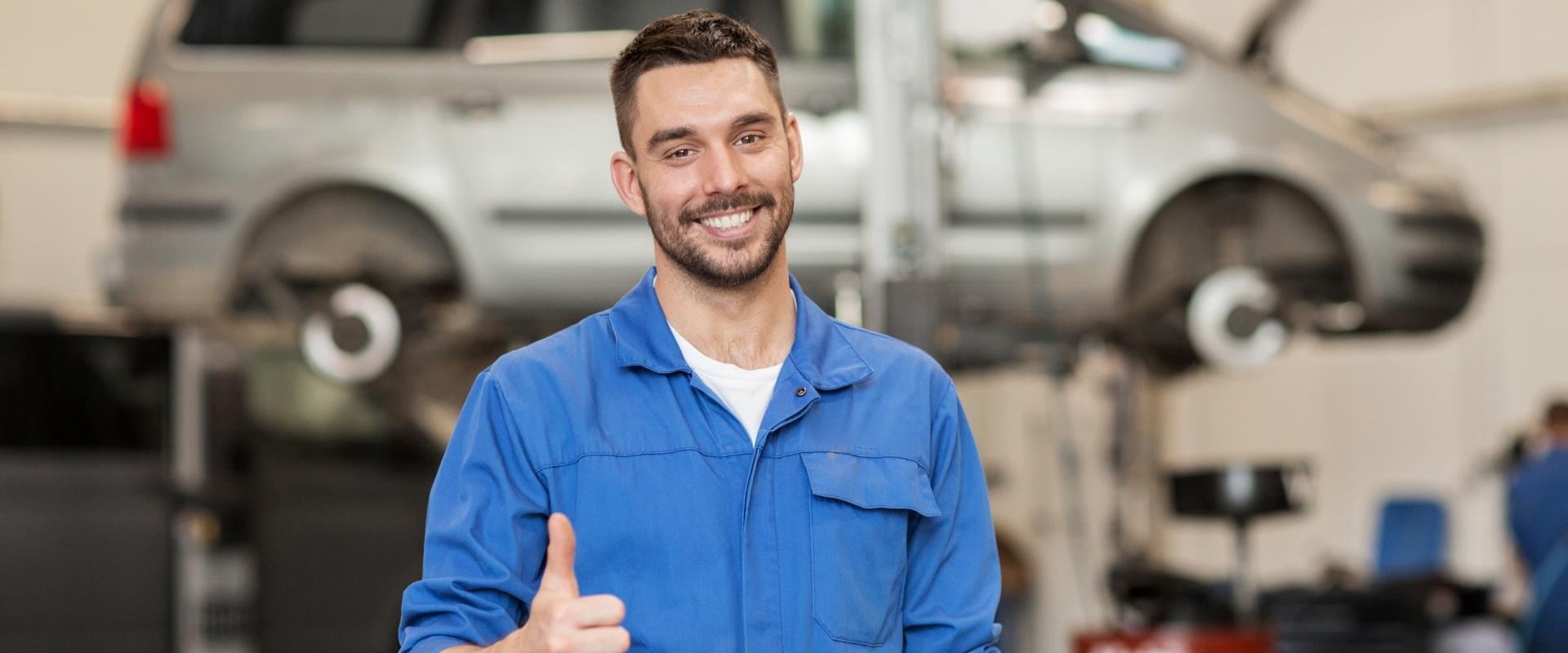 Ein lächelnder Mechaniker zeigt in einer Werkstatt seinen Daumen nach oben.