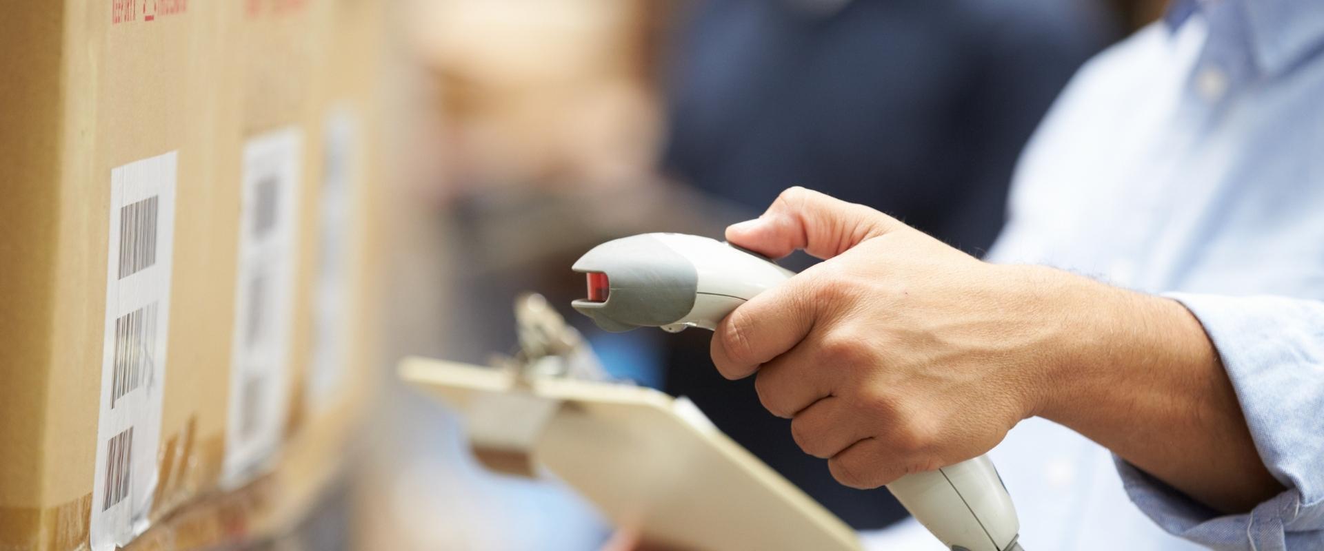 Eine Person scannt einen Karton mit einem Barcode-Scanner.