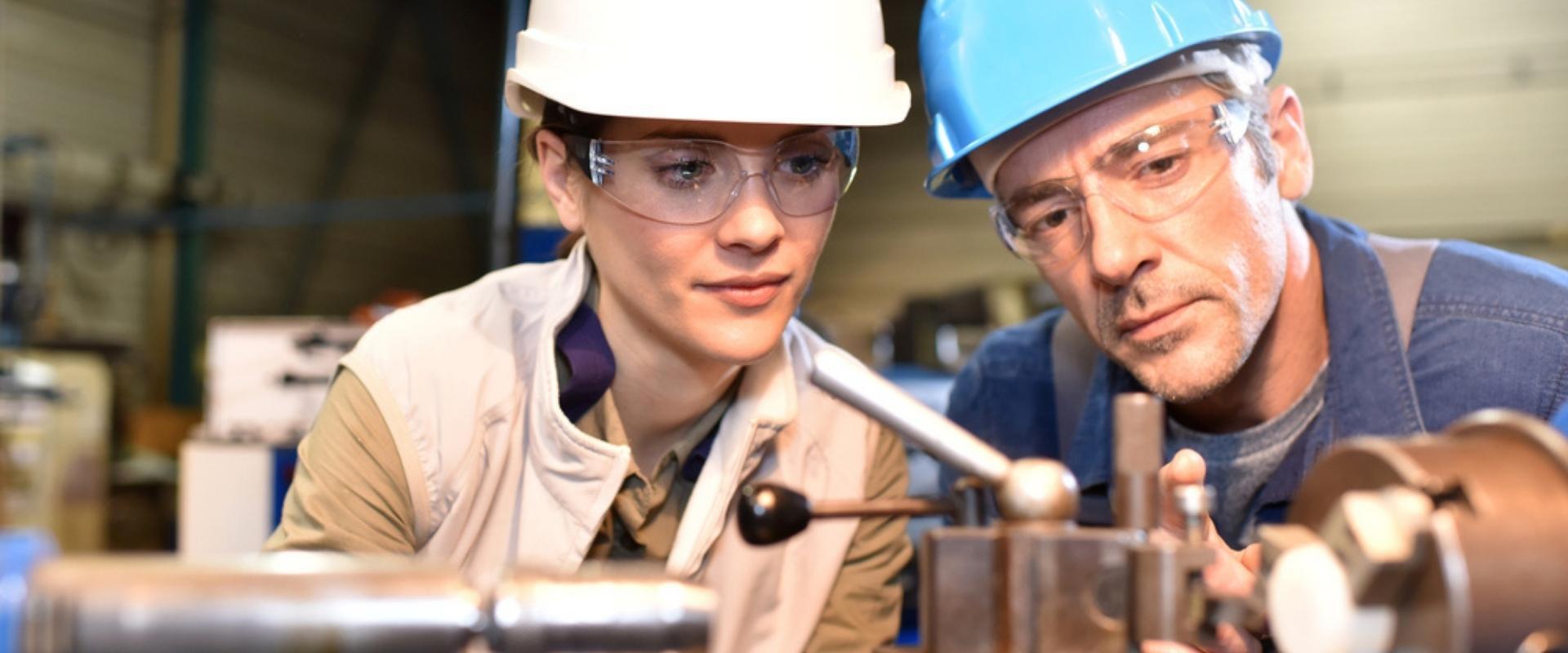 Ein Mann und eine Frau arbeiten in einer Fabrik an einer Maschine.