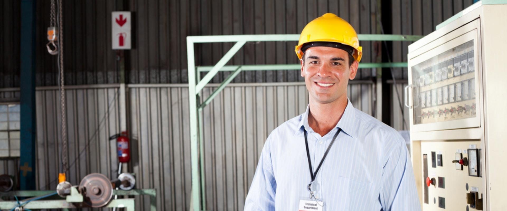 Ein Mann mit einem Schutzhelm steht in einer Fabrik.