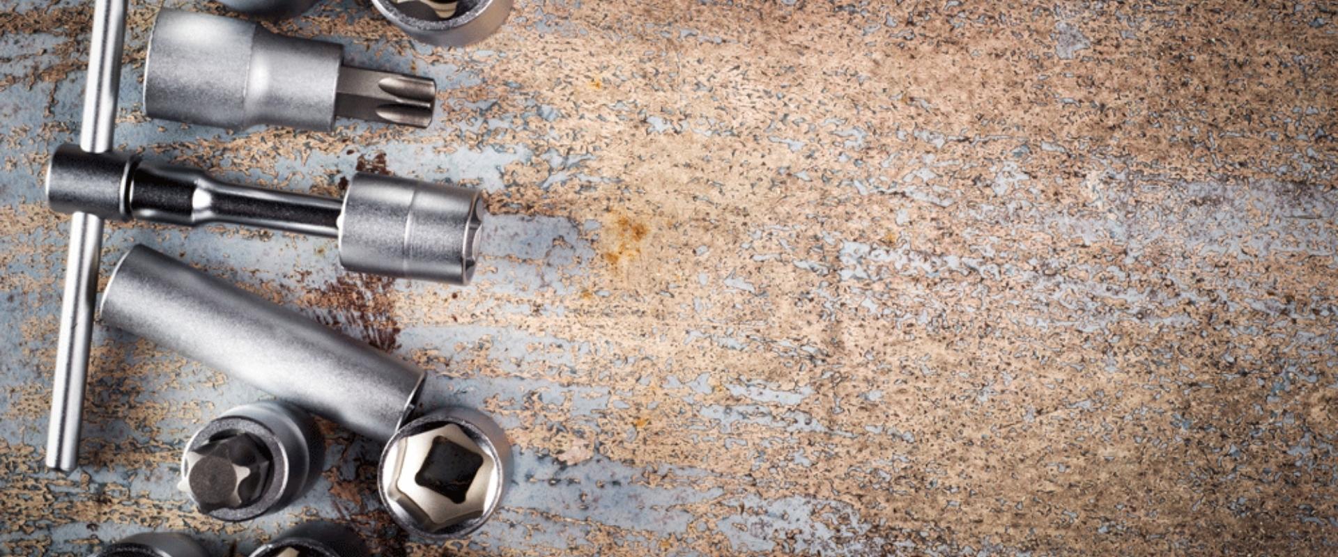 Ein Haufen Werkzeuge und Muttern liegen auf einer Metalloberfläche.