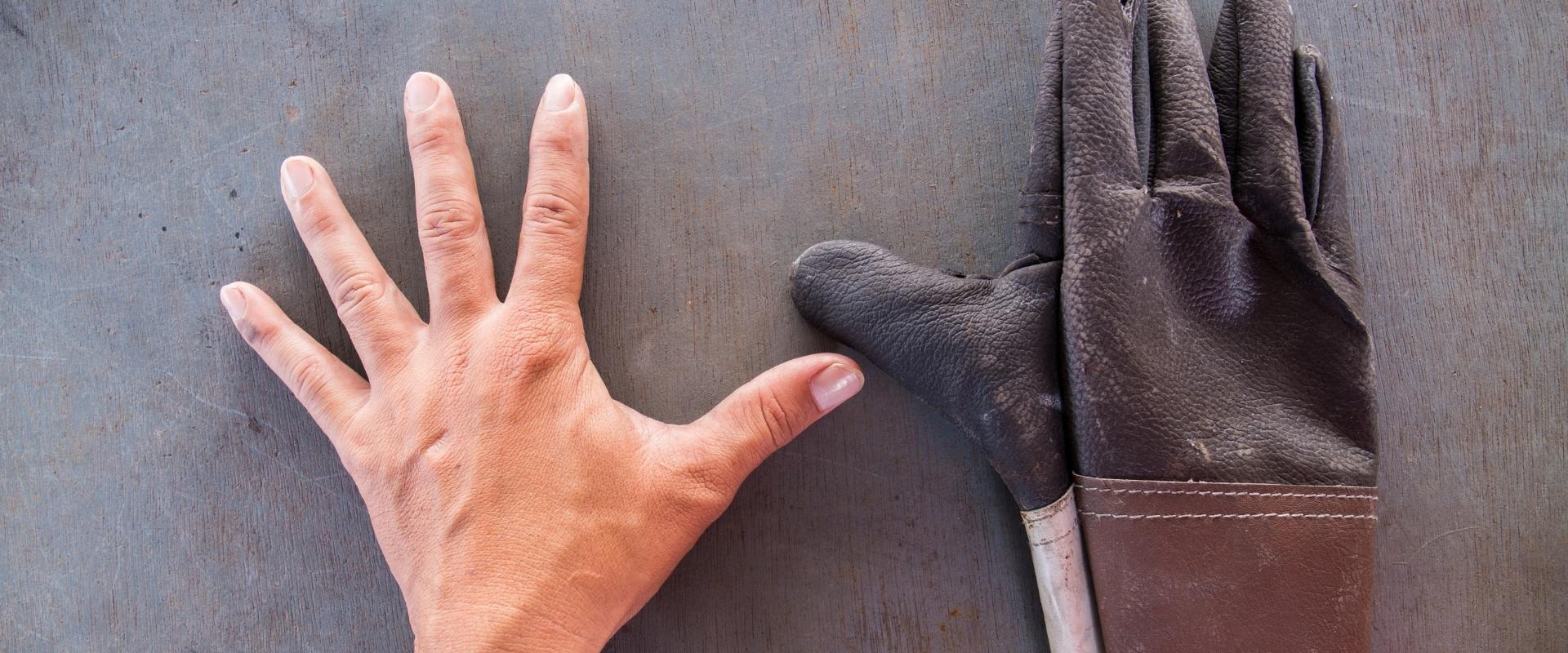 Die Hand einer Person wird neben einem Paar Handschuhe gemessen.