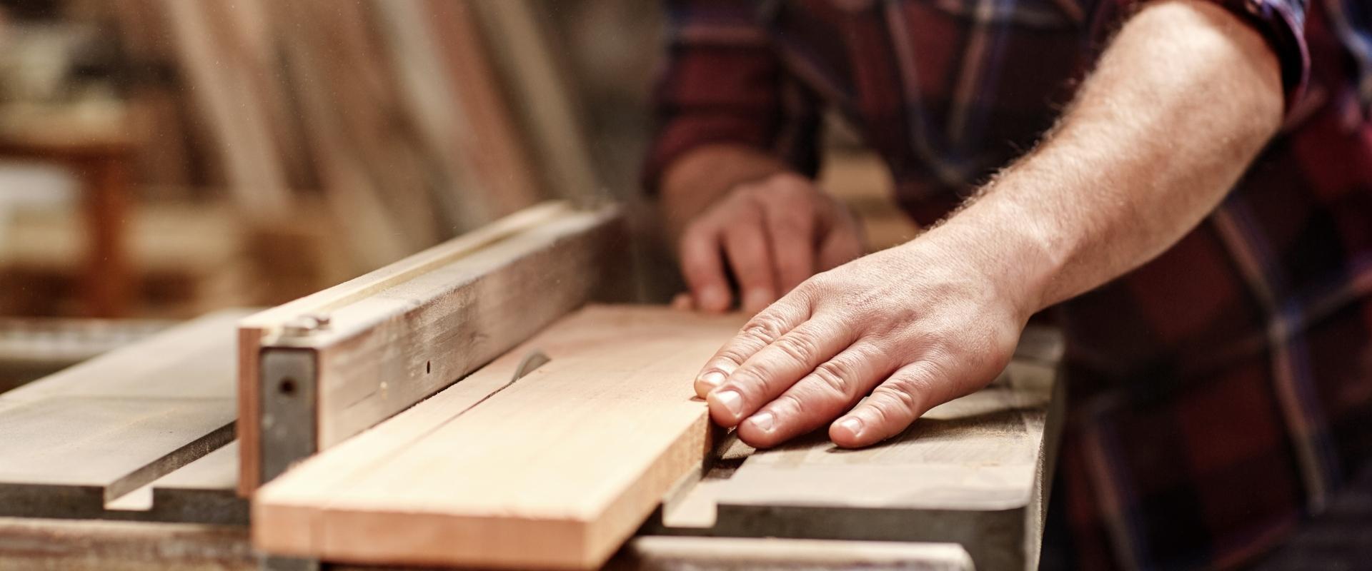 Ein Mann schneidet ein Stück Holz auf einer Tischkreissäge.