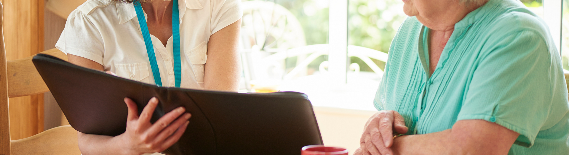 Two people sit on a couch, looking at a laptop together in a bright room.