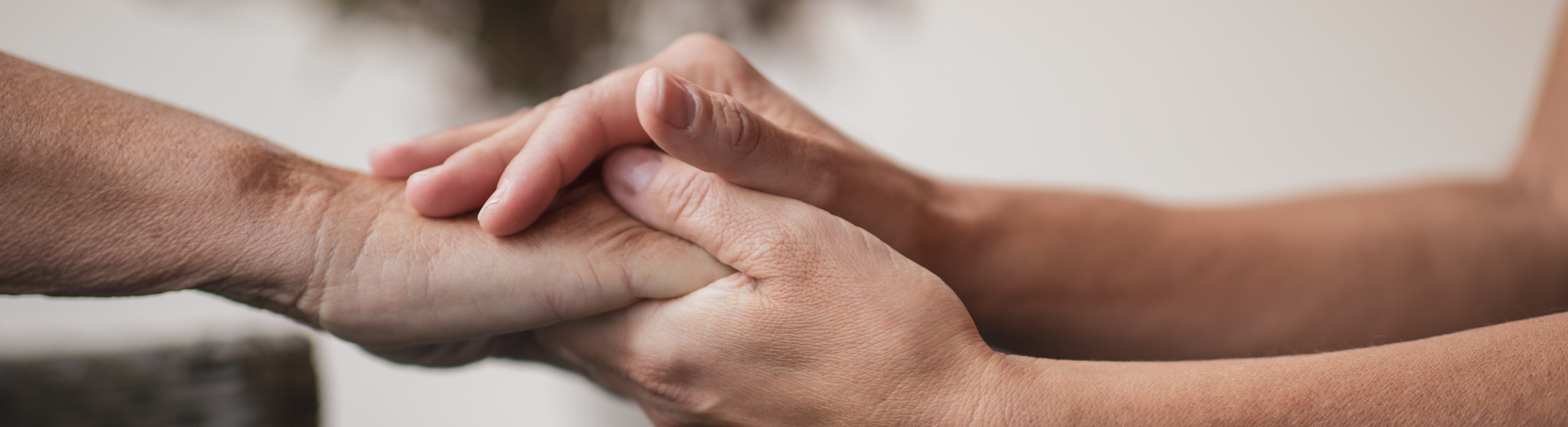 Two hands clasped in a supportive handshake over a blurred background