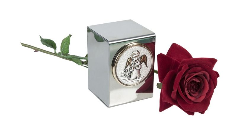 Red rose beside a silver memorial keepsake box with an engraved oval cameo.