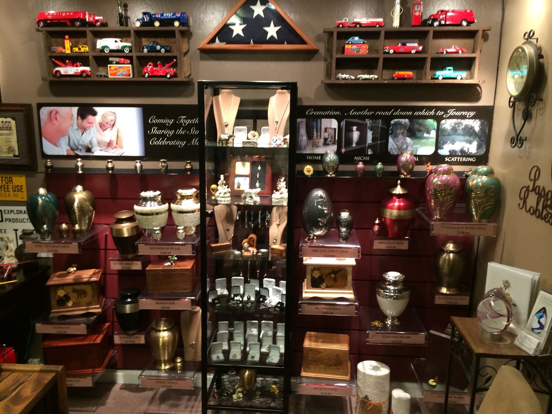 Memorial display with flags, urns, framed photos, and candles arranged on shelves and tables
