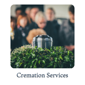 Cremation urn on green foliage with blurred mourners in the background