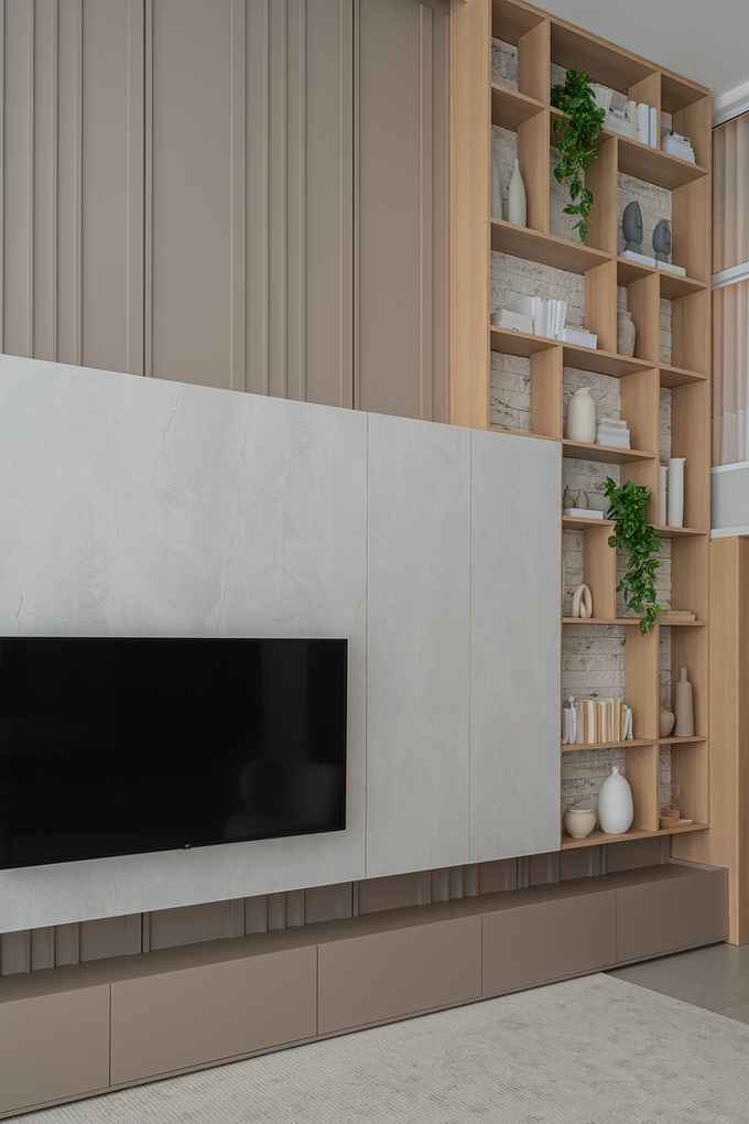 Sala de estar moderna con televisor montado en la pared, estanterías de madera y decoración en tonos beige neutros.