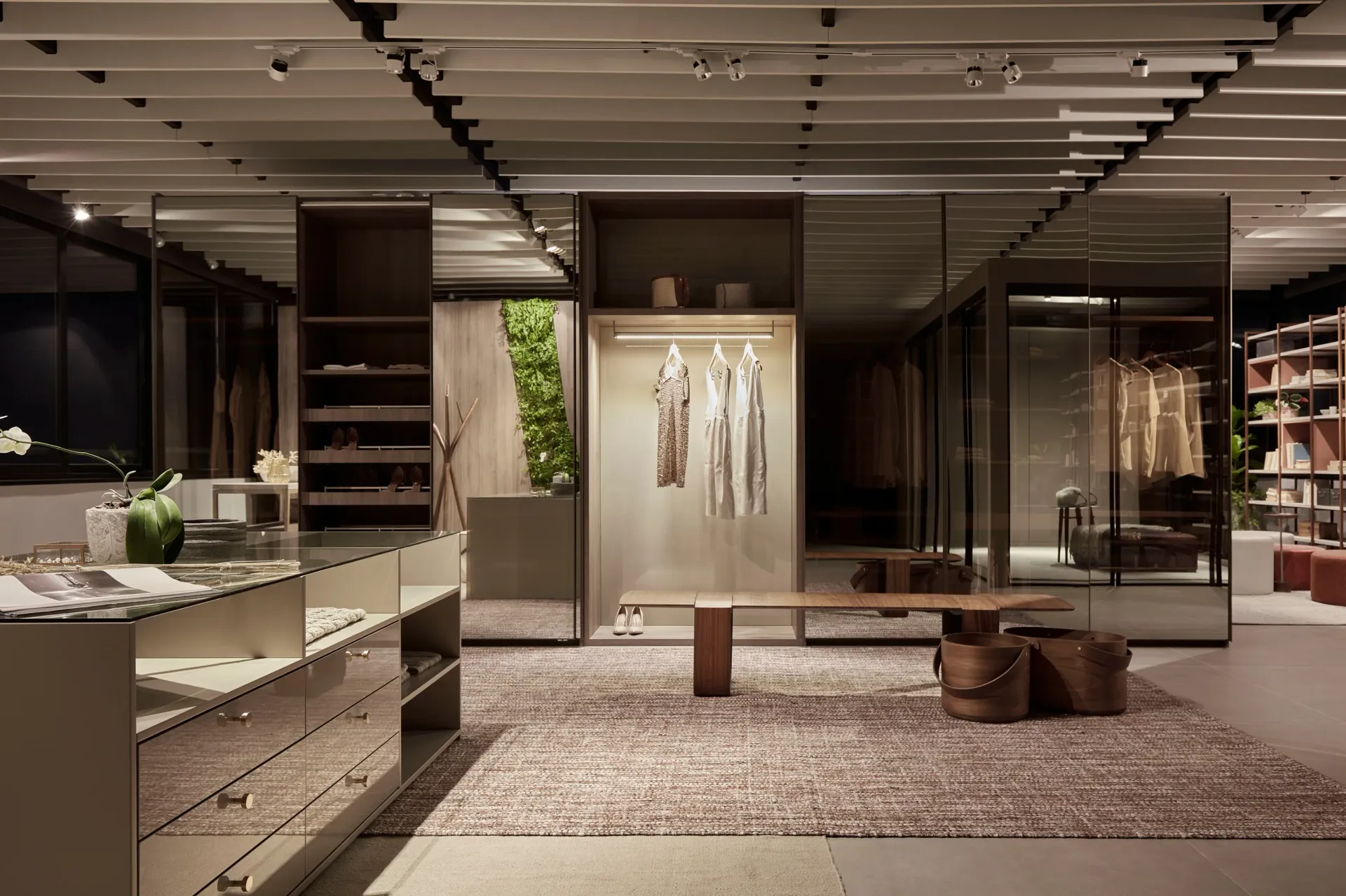 Interior de boutique de lujo moderna con estanterías abiertas, lámparas colgantes y expositores de ropa.