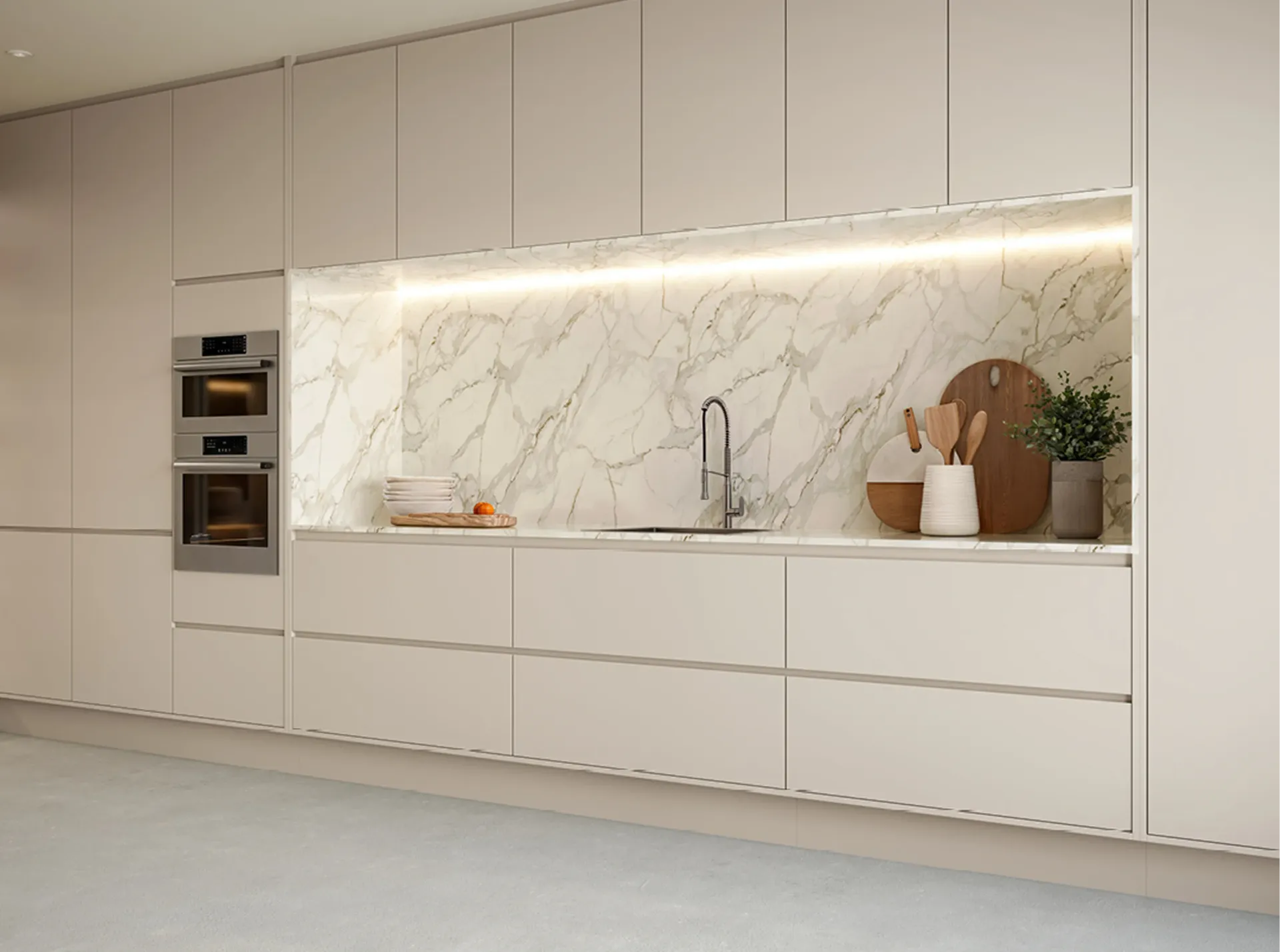 Cocina moderna minimalista con gabinetes blancos, salpicadero de mármol, horno empotrado e iluminación bajo los gabinetes.