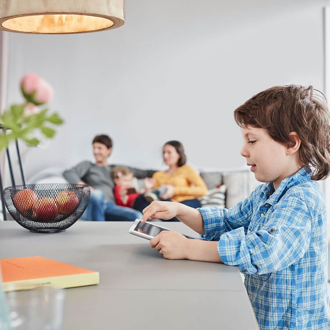Un niño pequeño está sentado en una mesa jugando con un teléfono celular.