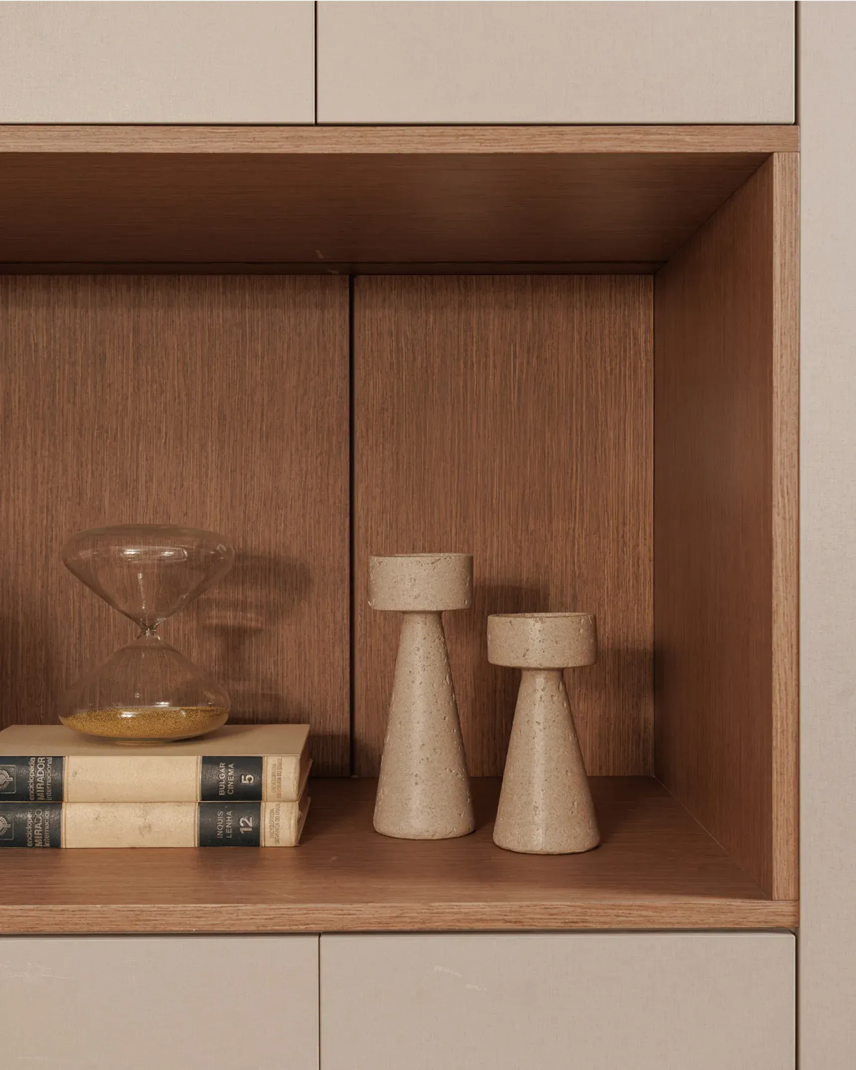 Estantería de madera con un cuenco de cristal, libros y dos pequeños jarrones decorativos de color beige.
