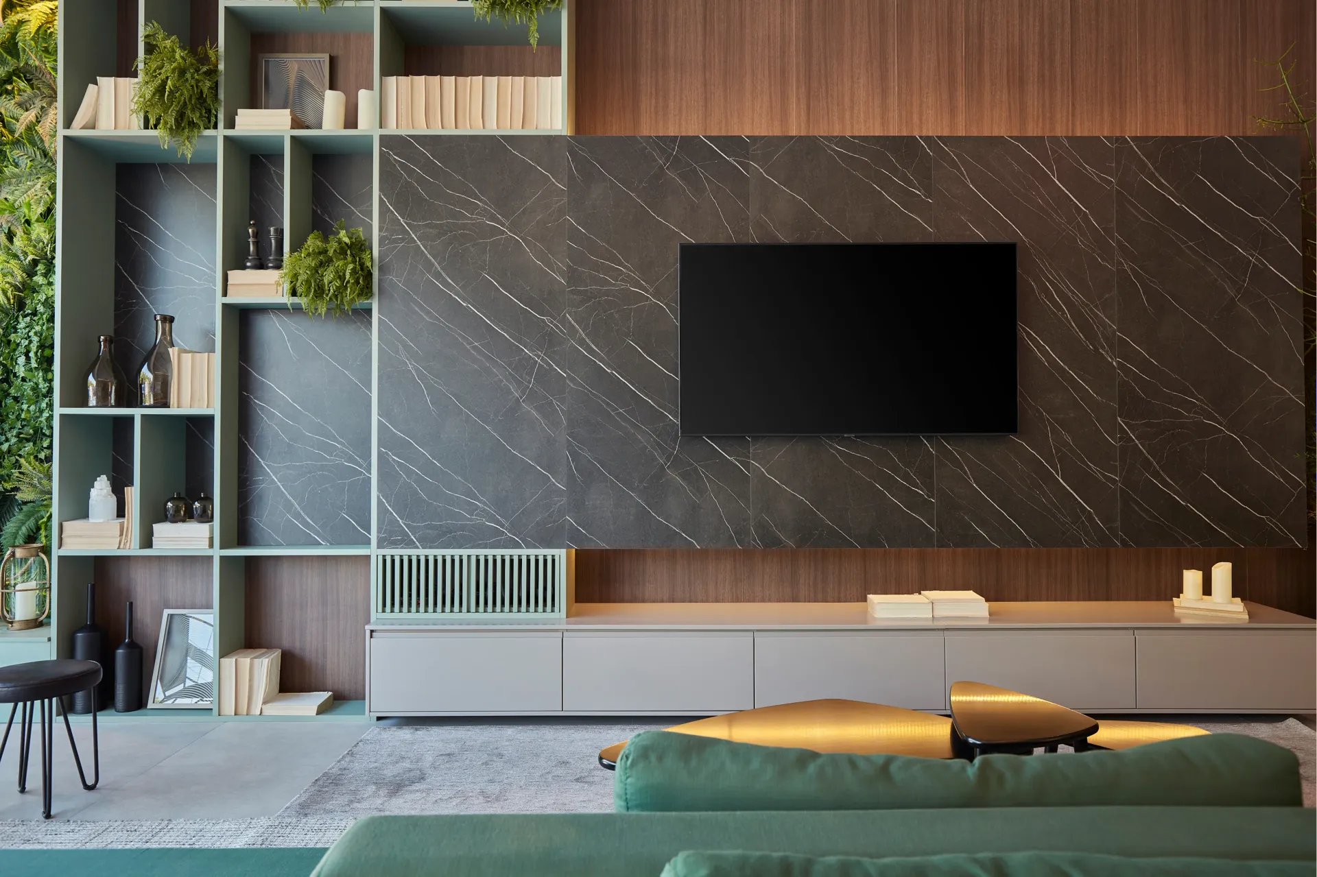 Sala de estar moderna con estanterías de madera, pared de mármol para el televisor, consola baja y sofá verde.