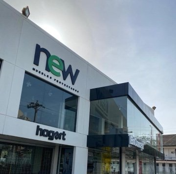 Exterior de tienda New con fachada blanca, ventanas de cristal y letreros negros.