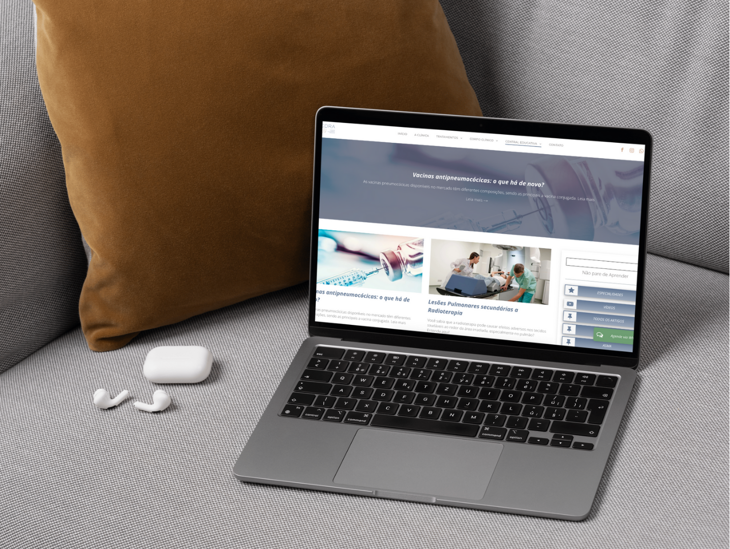 Um laptop está sobre um sofá ao lado de um travesseiro.