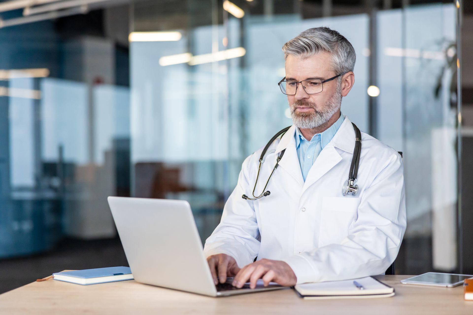 Médico usando jaleco branco utilizando o computador para divulgar seu consultório