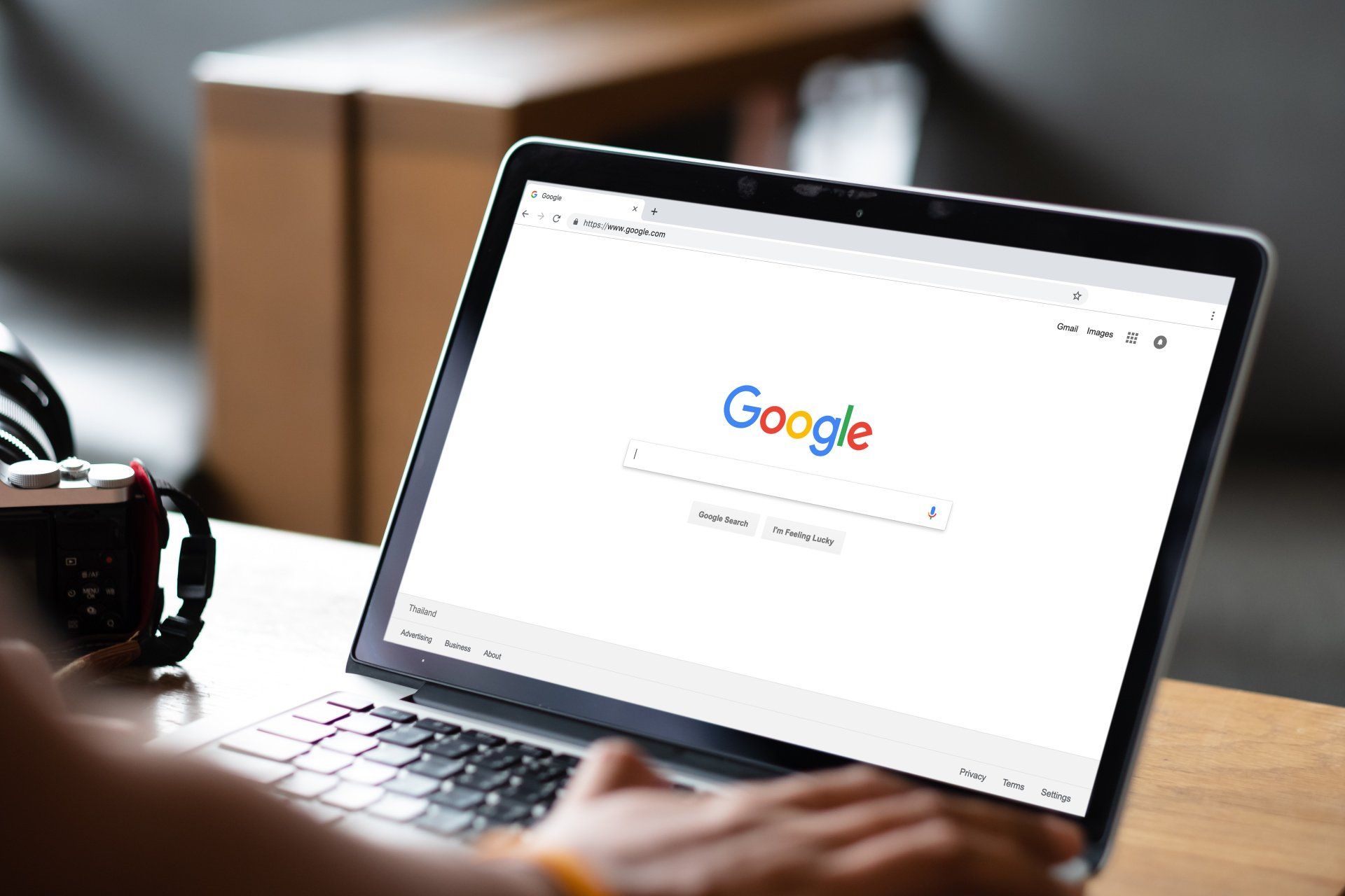 Uma pessoa está digitando em um laptop com uma barra de pesquisa do Google na tela.