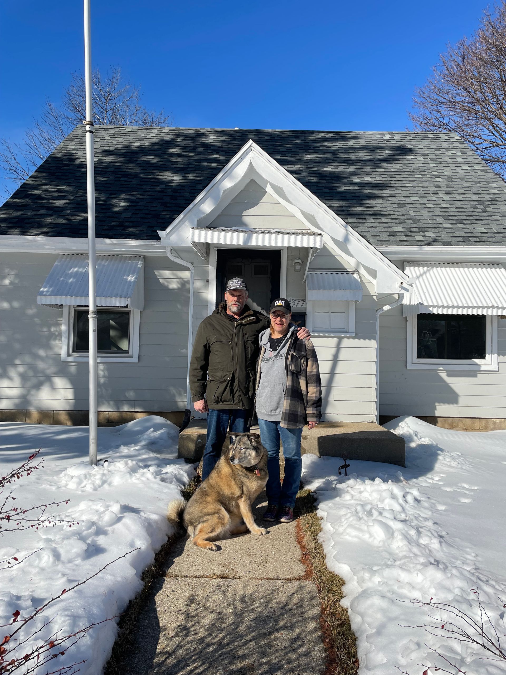 A man and woman holding a sold sign in front of a house