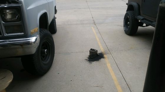 A white truck is parked next to a black truck in a parking lot